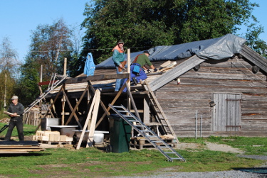 Män spånar om taket på gammal lada